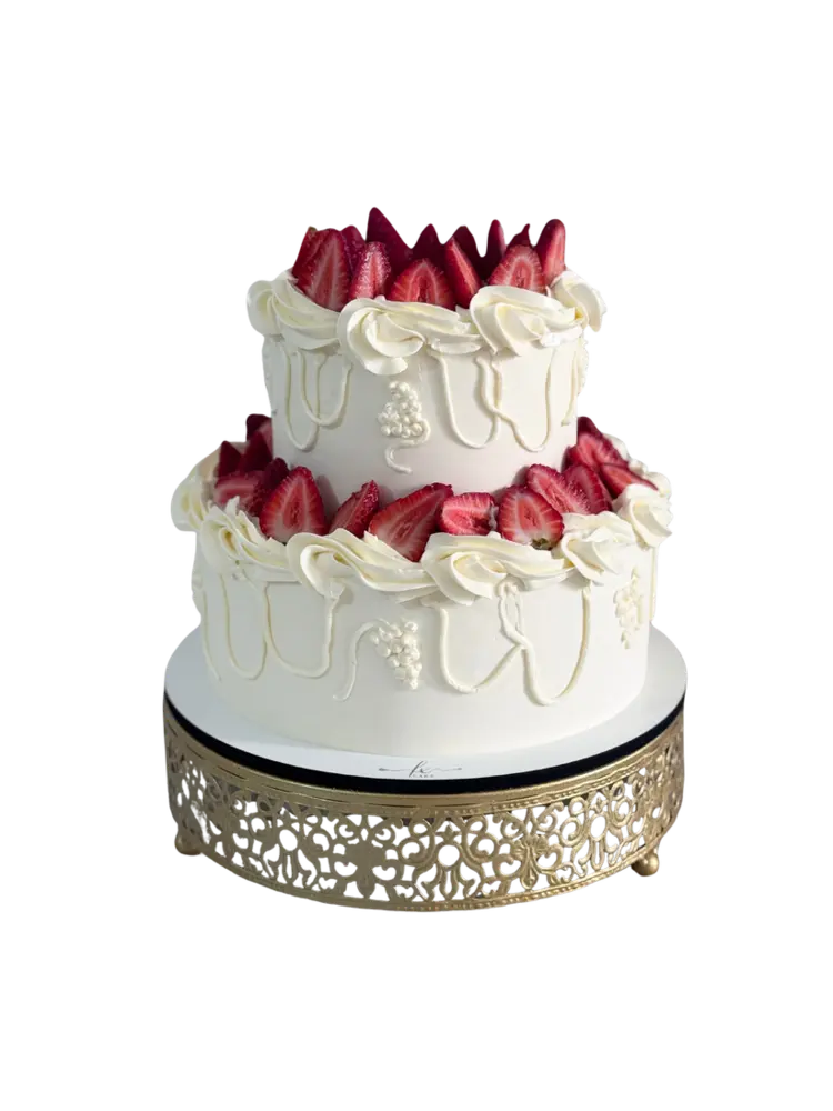 Bolo de dois andares com chantilly e morangos sobre suporte dourado