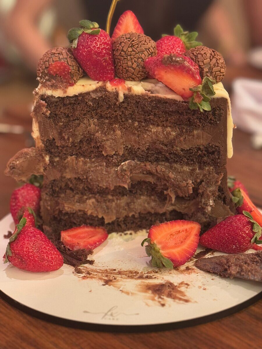 Fatia de bolo de chocolate com recheio dourado e morangos